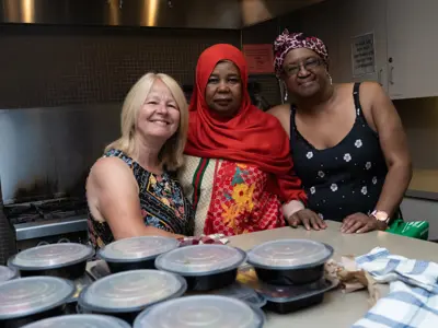 Group of people standing in front of stack of food in reusable containers
