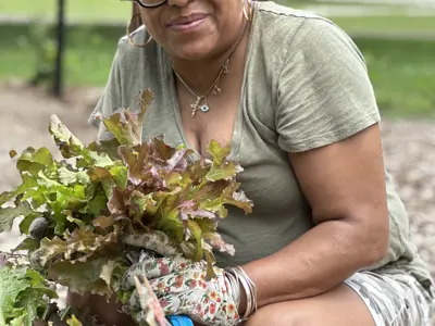 woman crouched down in a garden hold a plant