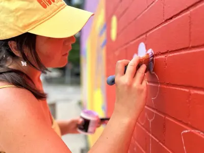 close up photo of a female artist painting a mural on a wall
