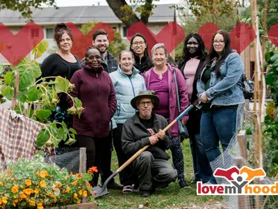 An group of gardeners posing for a photo in their community garden with tools