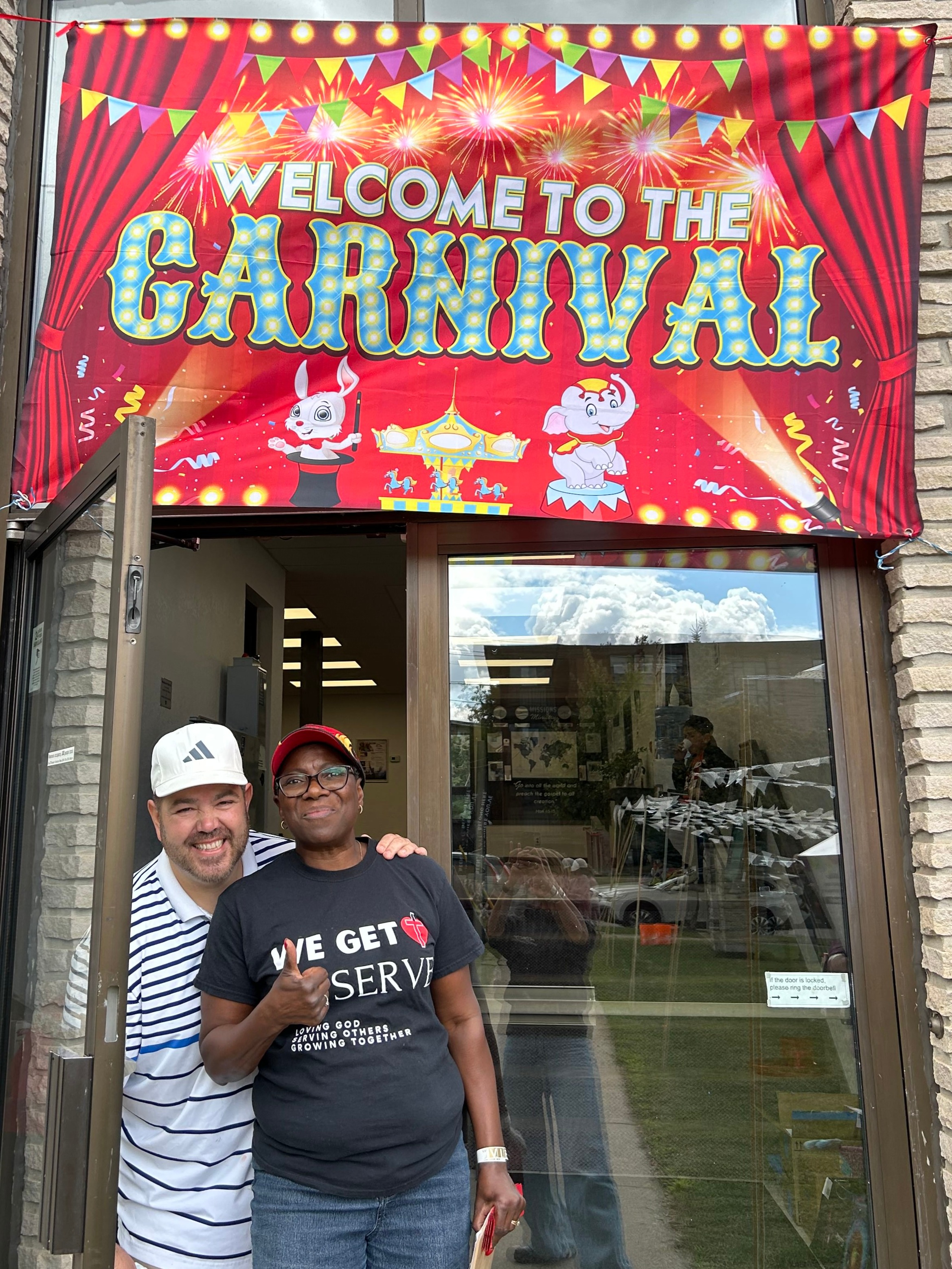 two people standing under sign that says welcome to the carnival
