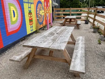a wooden picnic table on the left is a wall with a colourful mural