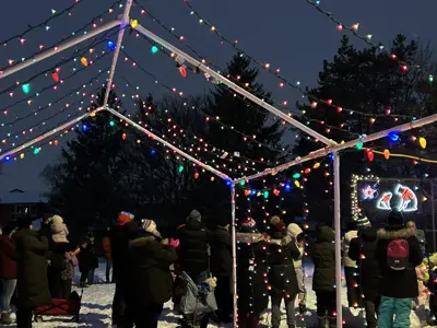 people standing outside in the winter under a christmas light display