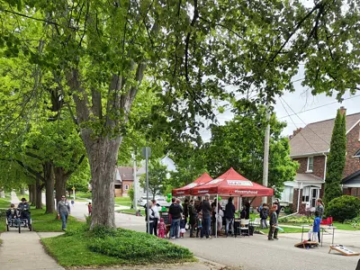 a street party with 2 pop up canopies in the middle of the road with all the neighbours standing by the tents