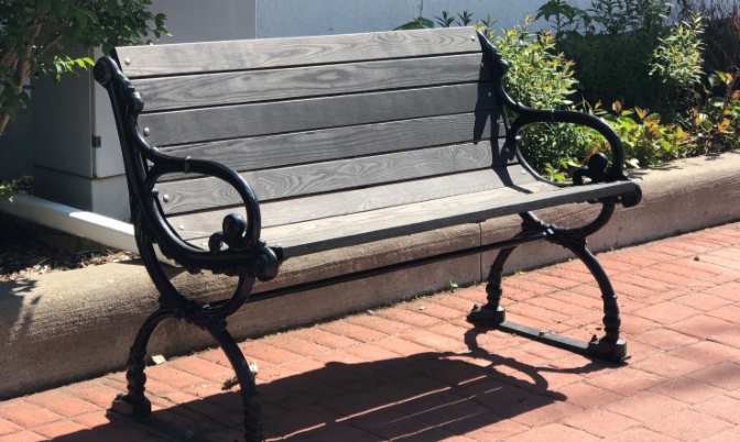 Wooden bench with metal arm rests