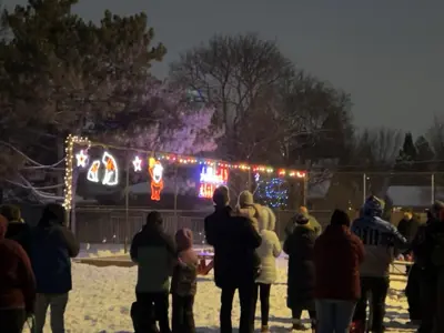 people standing outside in the winter looking at a christmas light display