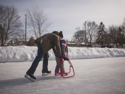 an adult helping a small child skate with a skating balance device