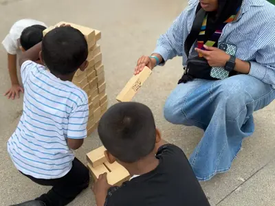  A youth teaching 3 smaller kids how to play giant Jenga