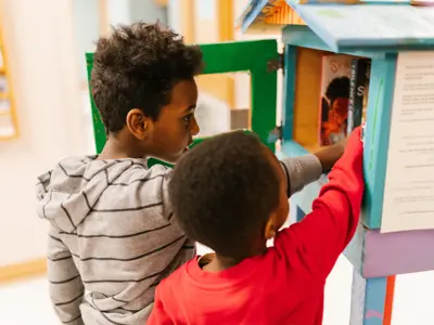 two kids reaching into a little library box